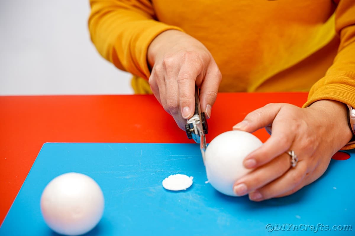 hand cutting ends off of styrofoam balls