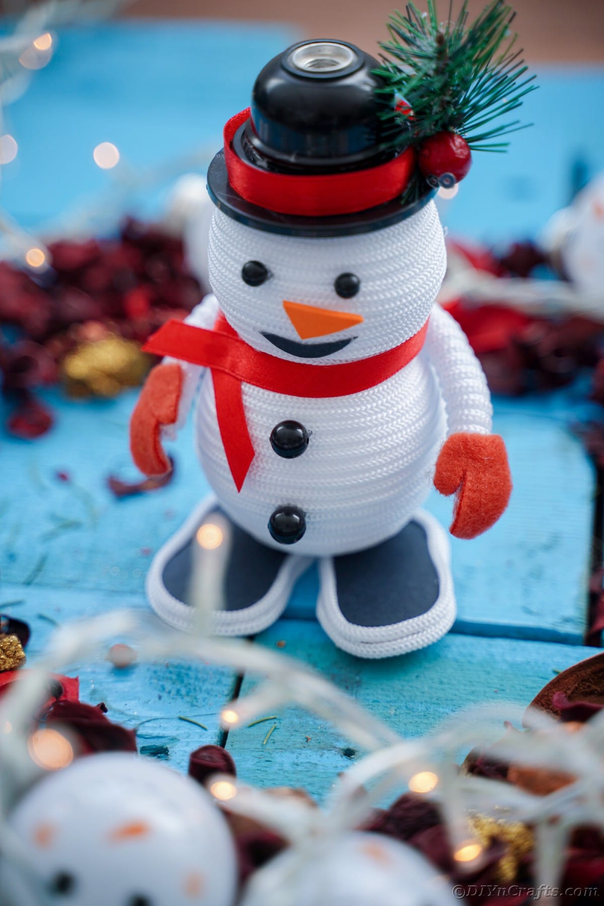 mini snowman decoration on blue table with pinecones