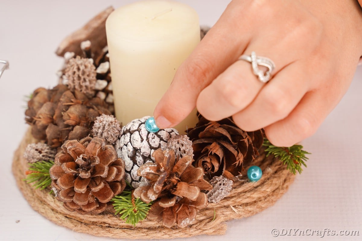 hand holding bead on top of pinecone