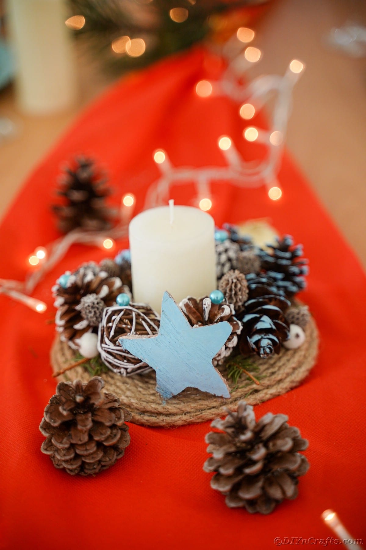 pinecone and star candle holder on red fabric
