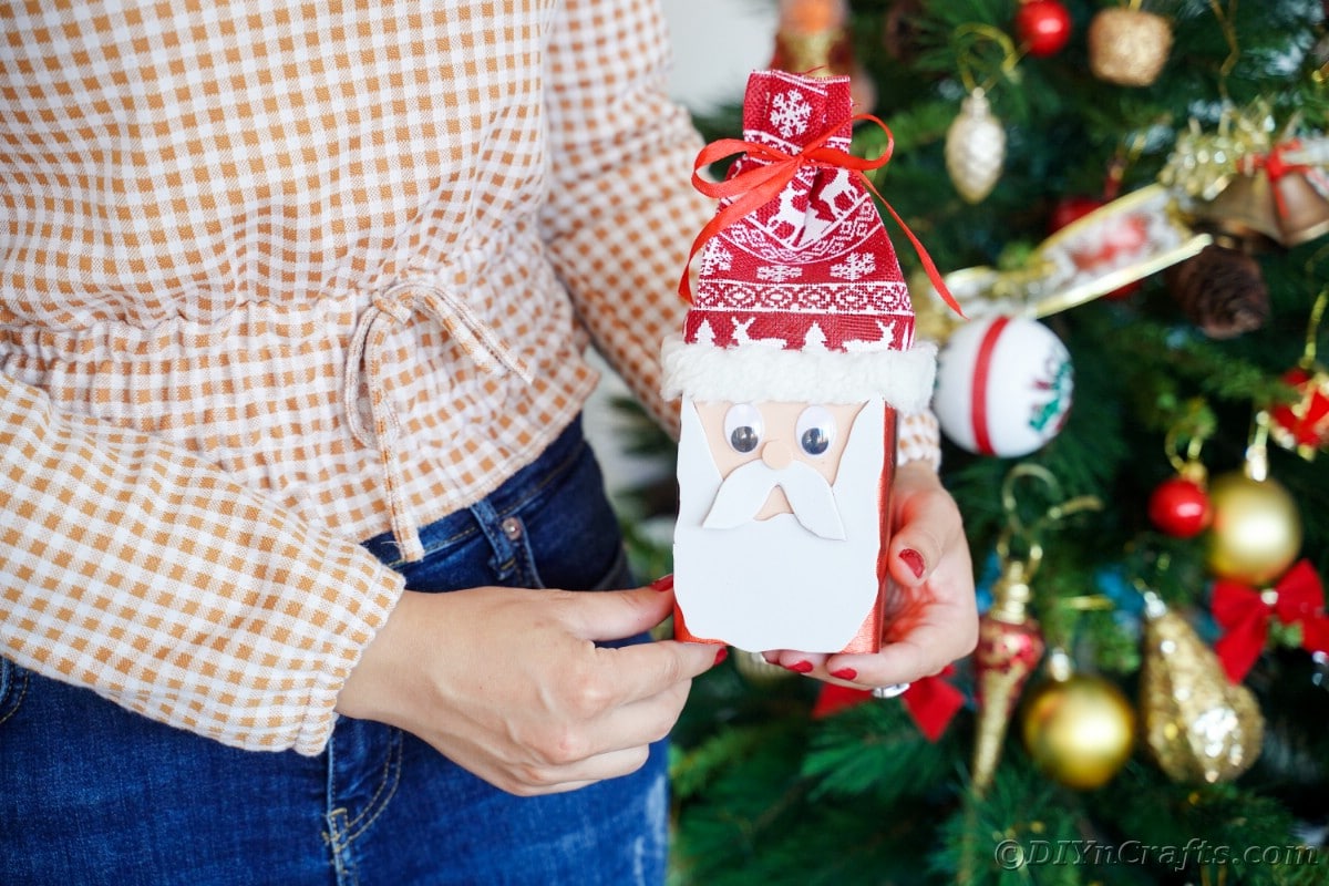 woman holding santa box in front of Christmas tree