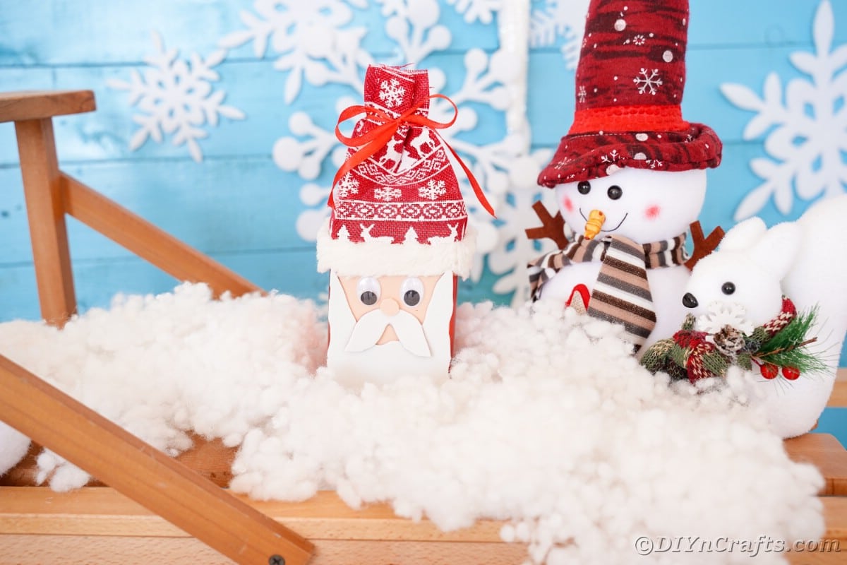 mini santa claus figure on fake snow on top of wooden bridge