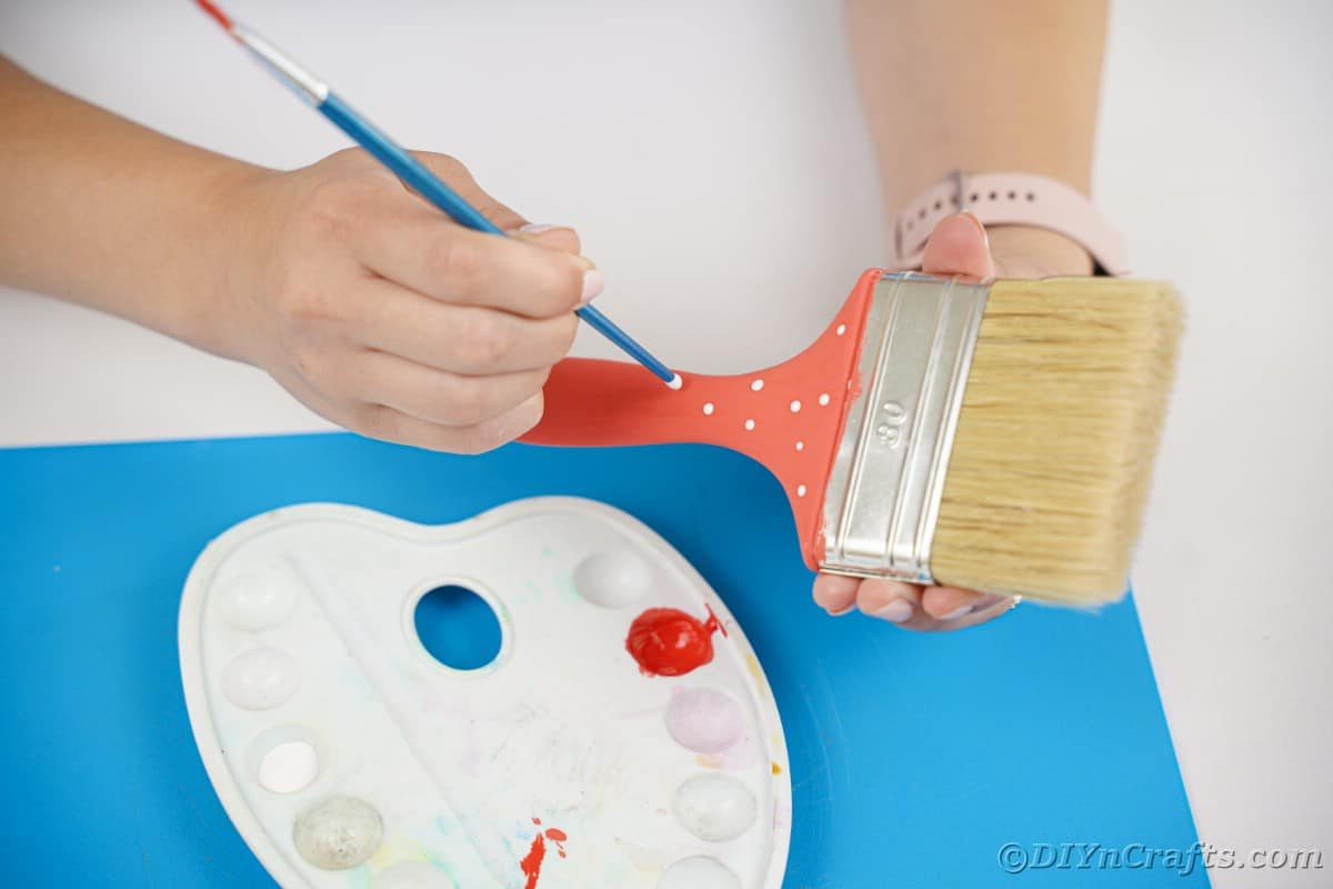 hand painting dots onto paintbrush handle