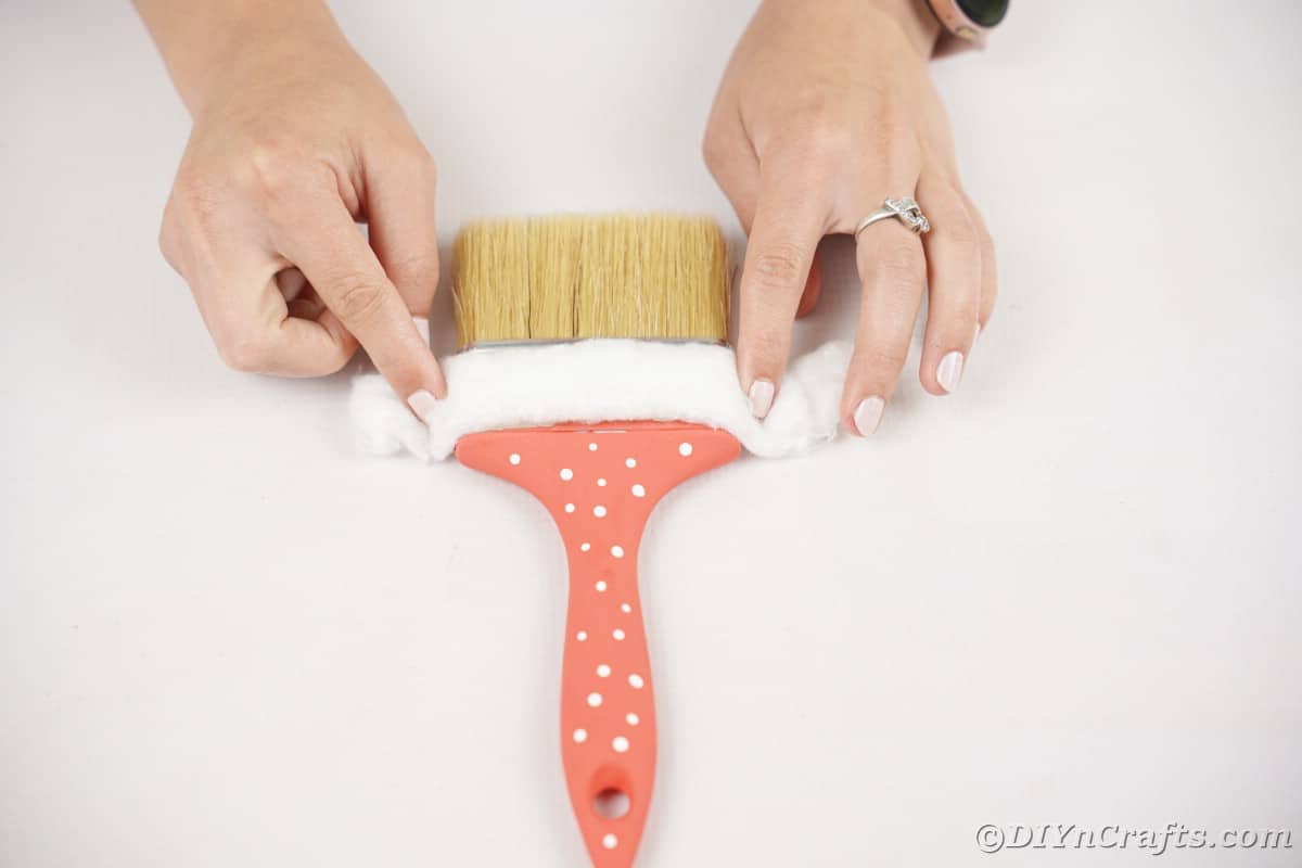 hands gluing cotton balls onto paintbrush