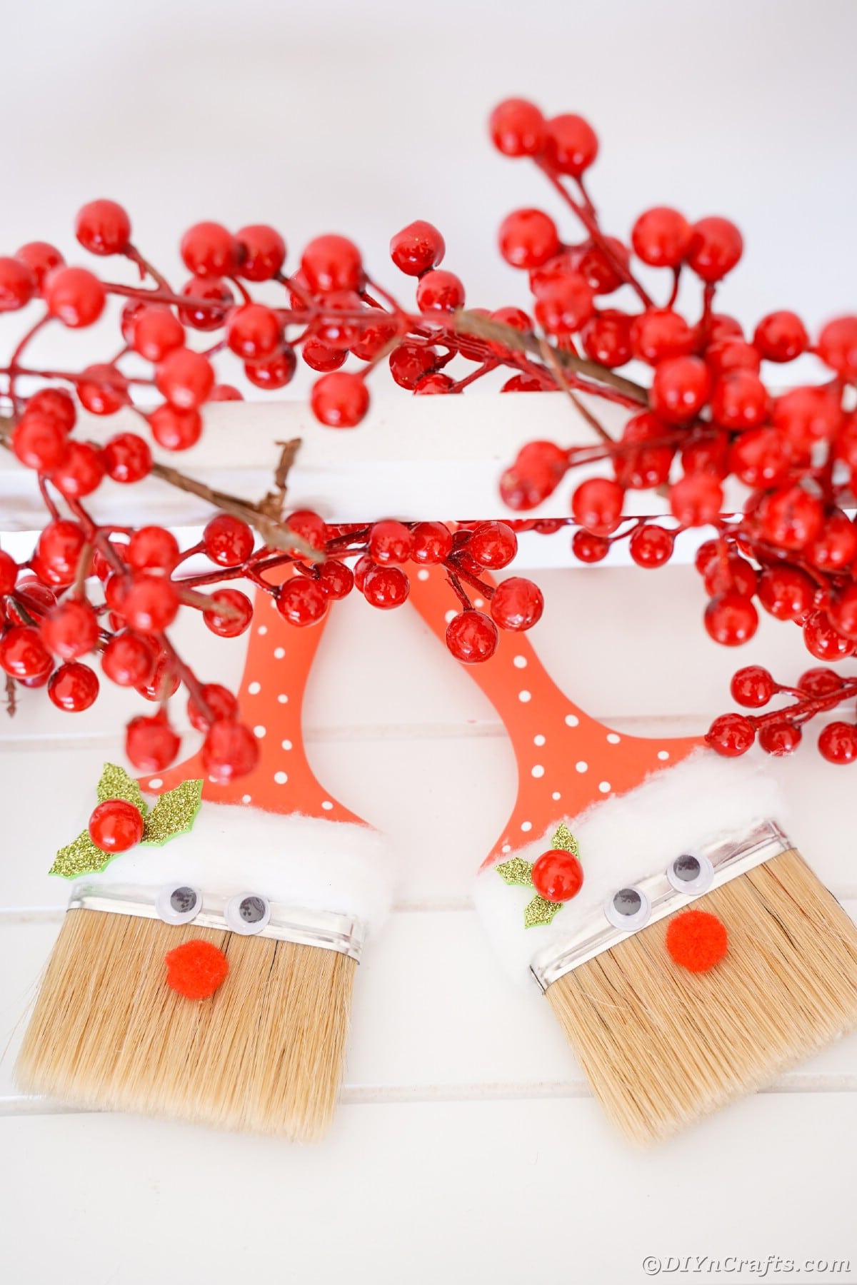 santa paintbrushes on table with holly berries