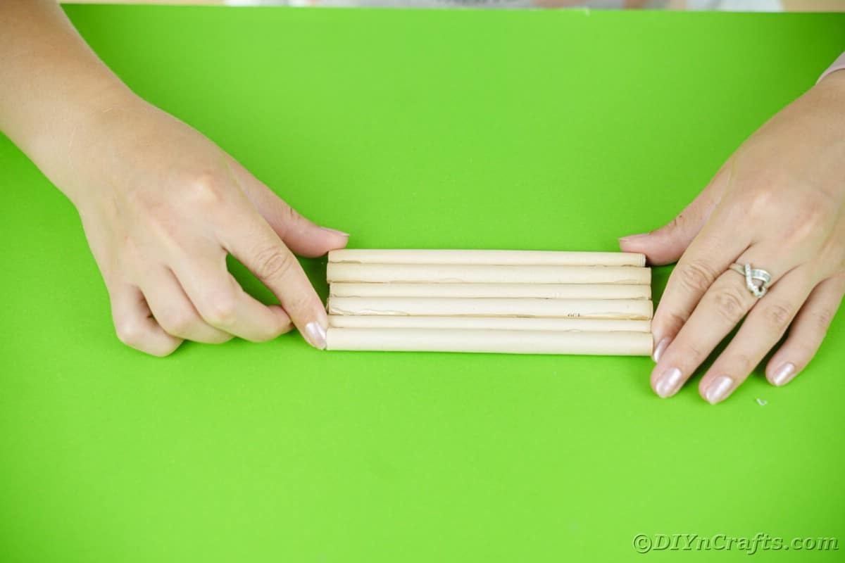 hands holding paper logs together on green table