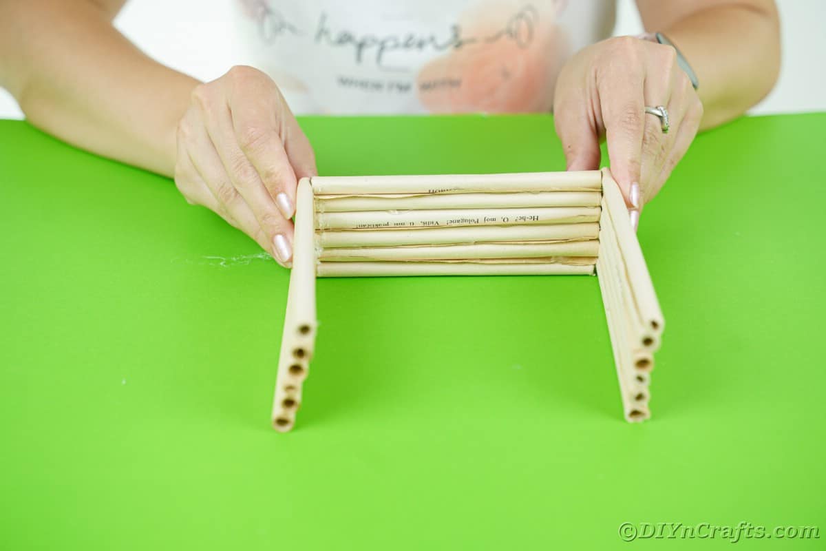hands holding paper log walls together for workshop on green table