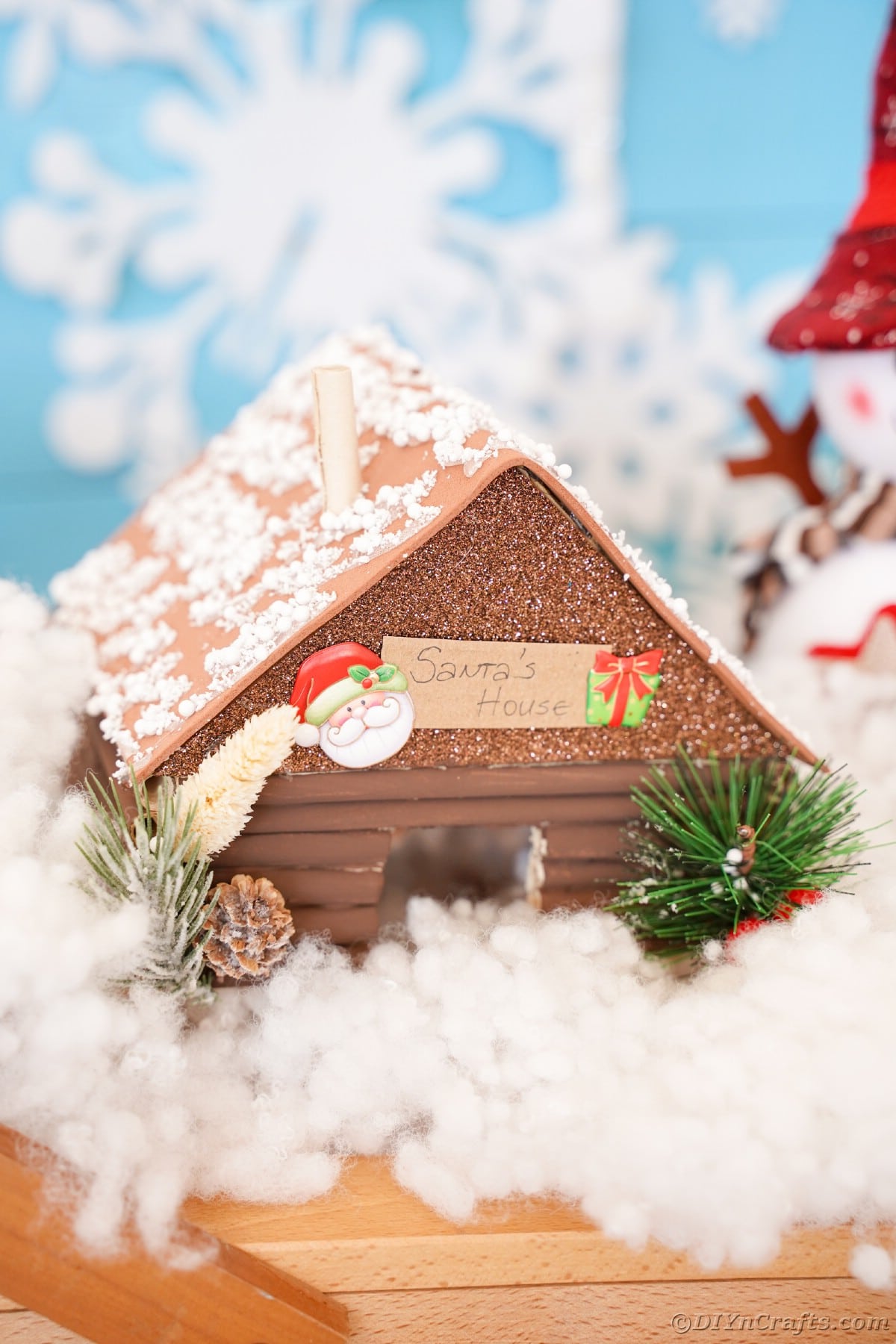 brown log cabin sitting in front of blue snowflake background on table