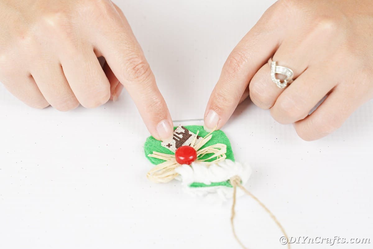 hands gluing reindeer fabric onto green ice skate ornament
