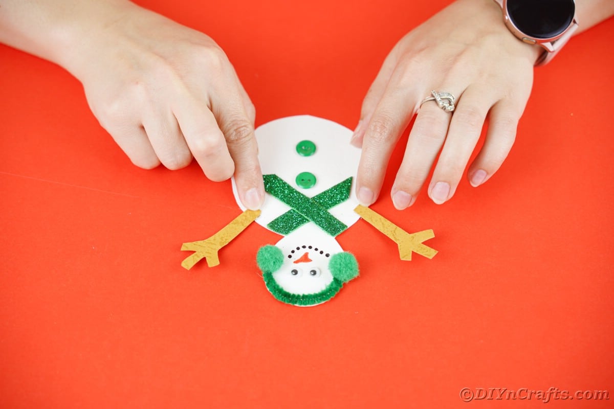 hands putting arms on snowman