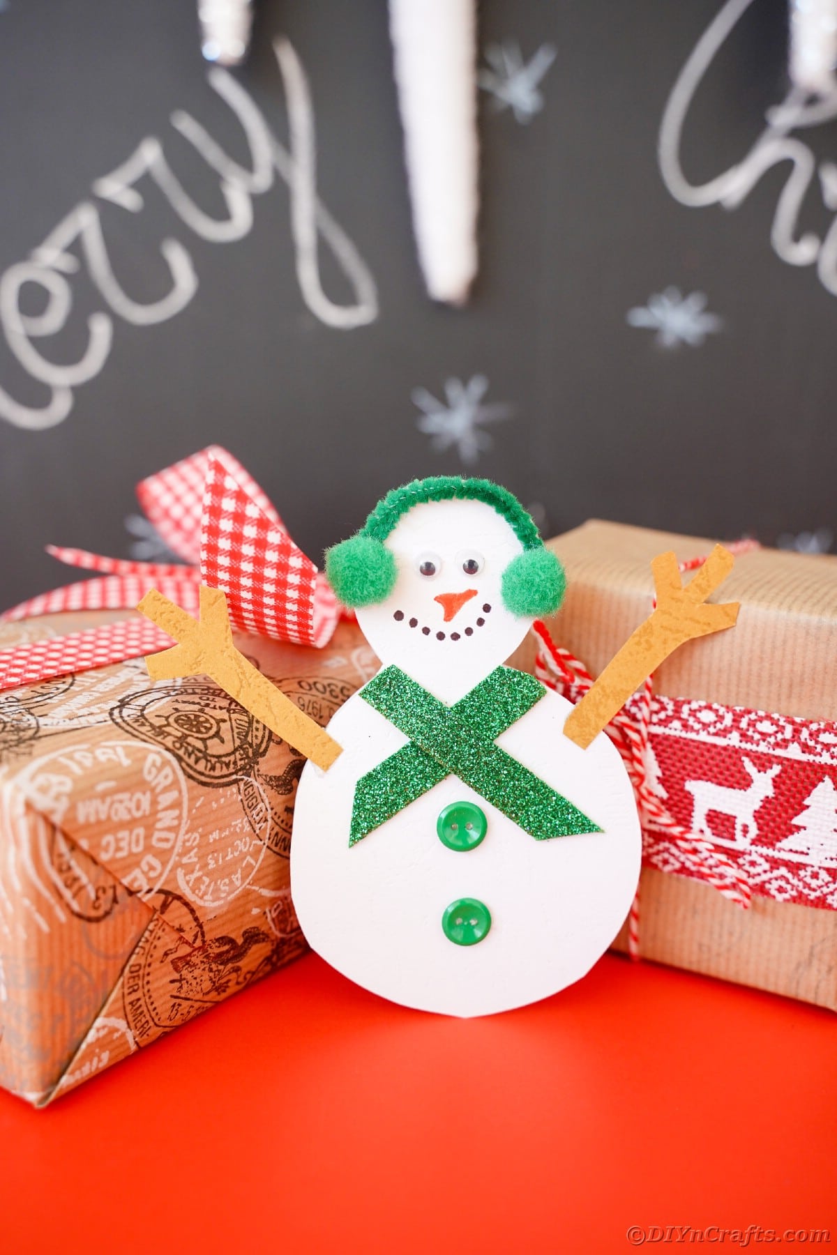 paper snowman with gifts by chalkboard