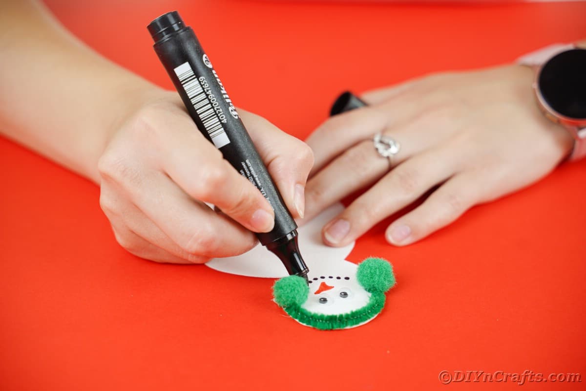 hands holding snowman card and adding black dots