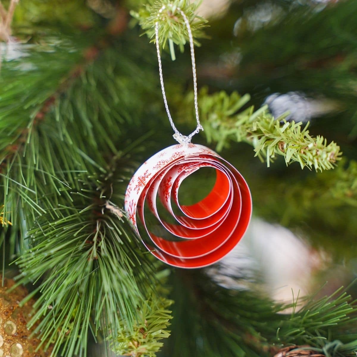 ornament iz rdečega in belega papirja, ki visi na božičnem drevesu
