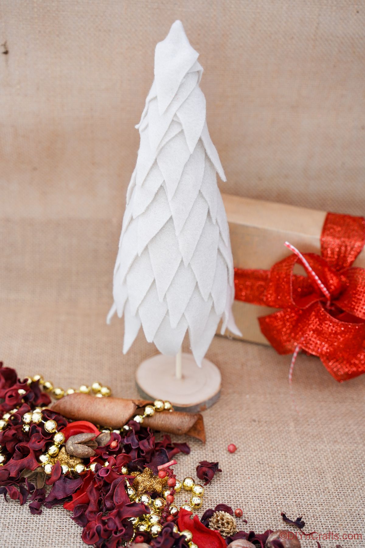 božično drevo iz kremne tkanine na leseni mizi s prazničnim dekorjem