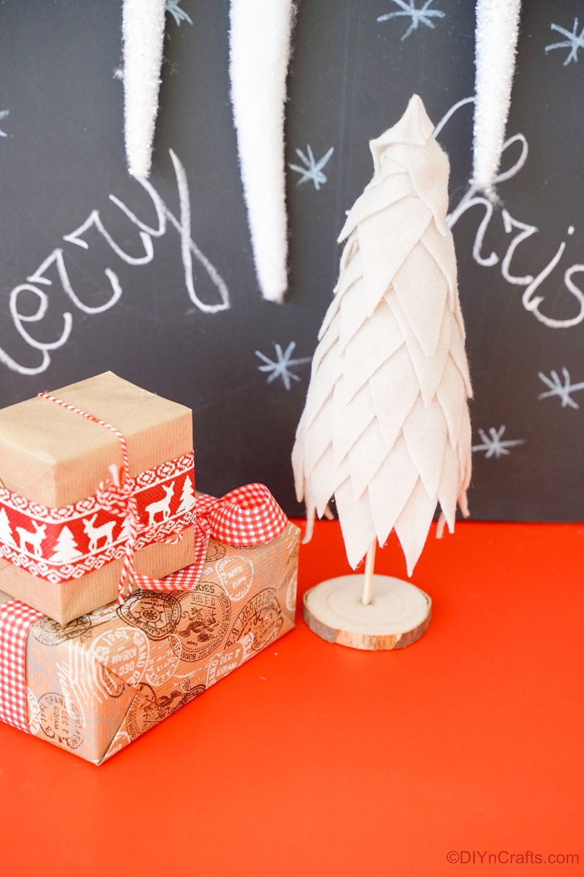 cream fabric Christmas tree sitting on red table by chalkboard