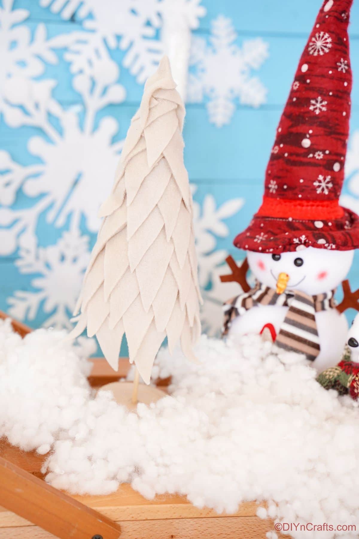 mini fabric tree on table with fake snow and fake snowman toy