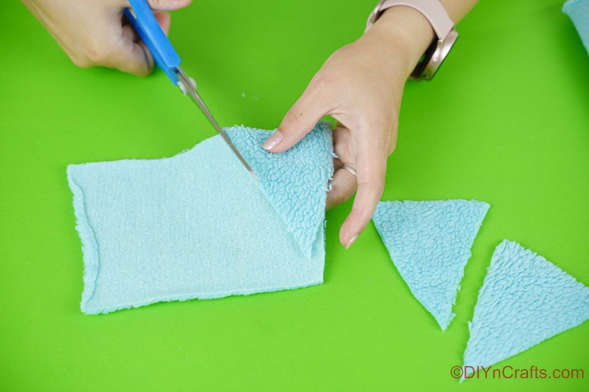cutting triangles of blue fabric with blue scissors