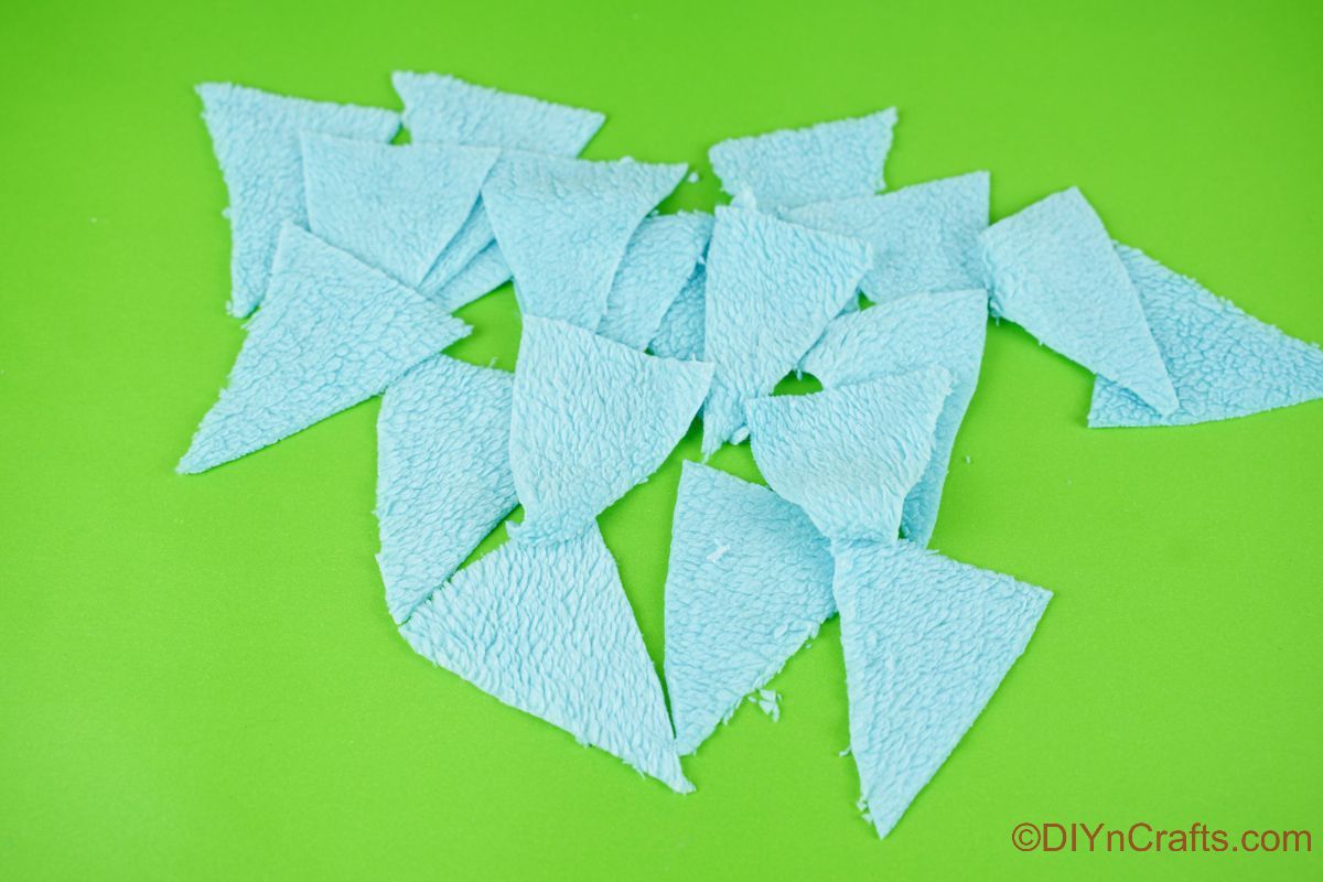 modri tkaninski trikotniki, ki ležijo na zeleni mizi