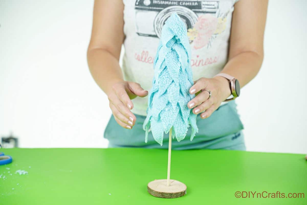 lady putting fabric tree on top of dowel base