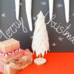 merry christmas chalkboard message behind red table with cream fabric christmas tree