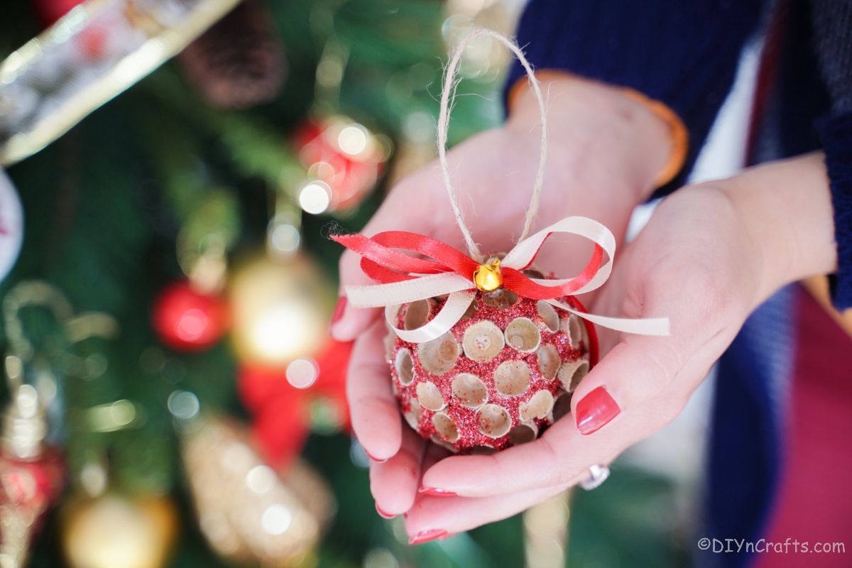 The glittering acorn cap ornament held in the hands of the women