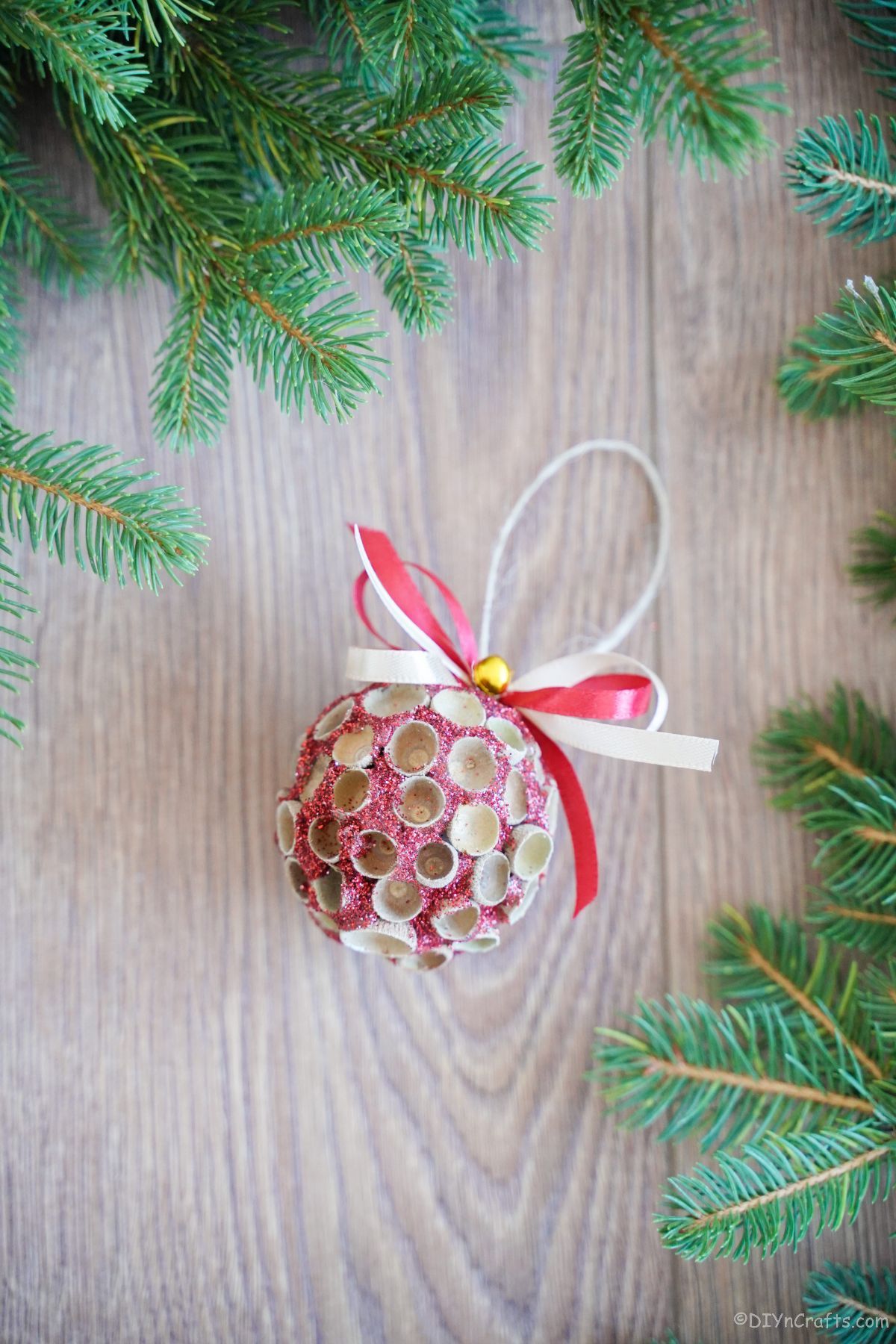 round pink glitter ornament on wood by greenery