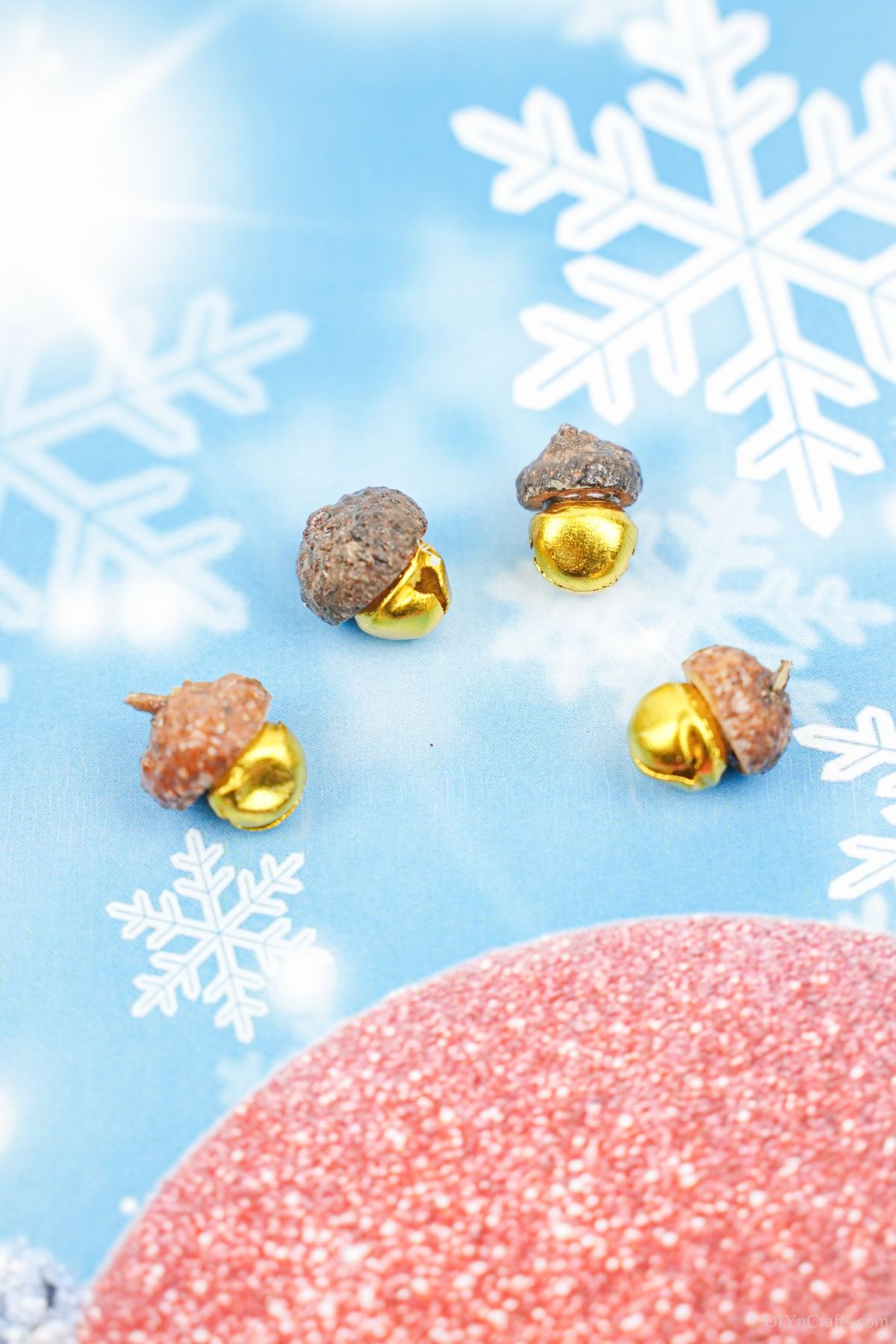 gold acorn cap jingle bells on blue paper with white fake snowflakes