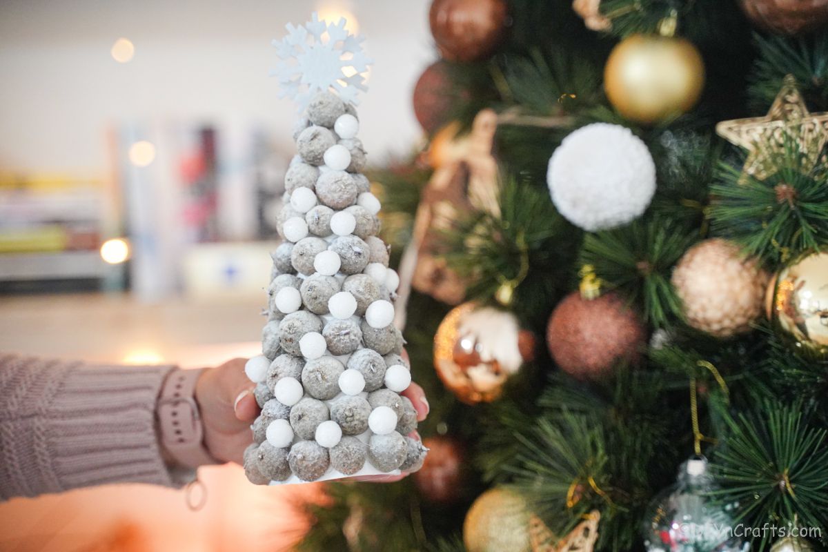 mini drevo z belim želodom pred zelenim božičnim drevescem polne velikosti