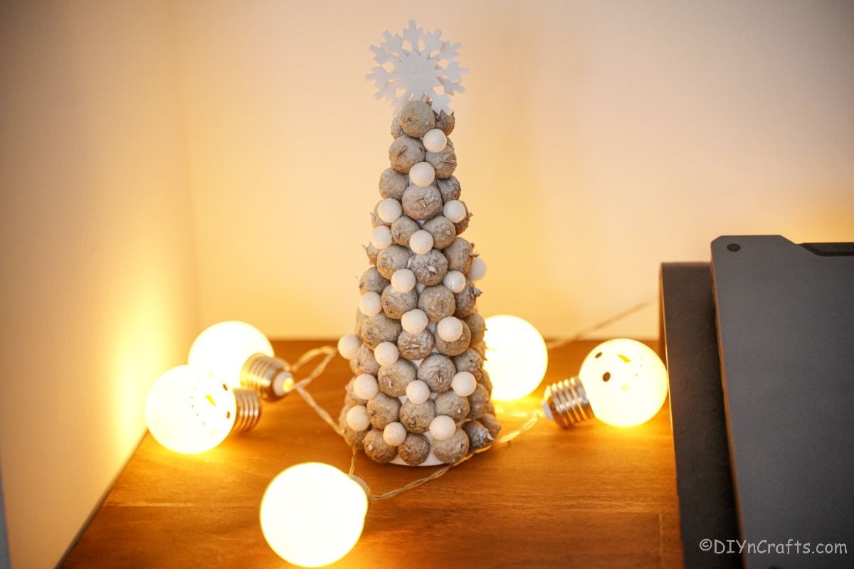 belo mini drevo na stranski mizi z lučkami