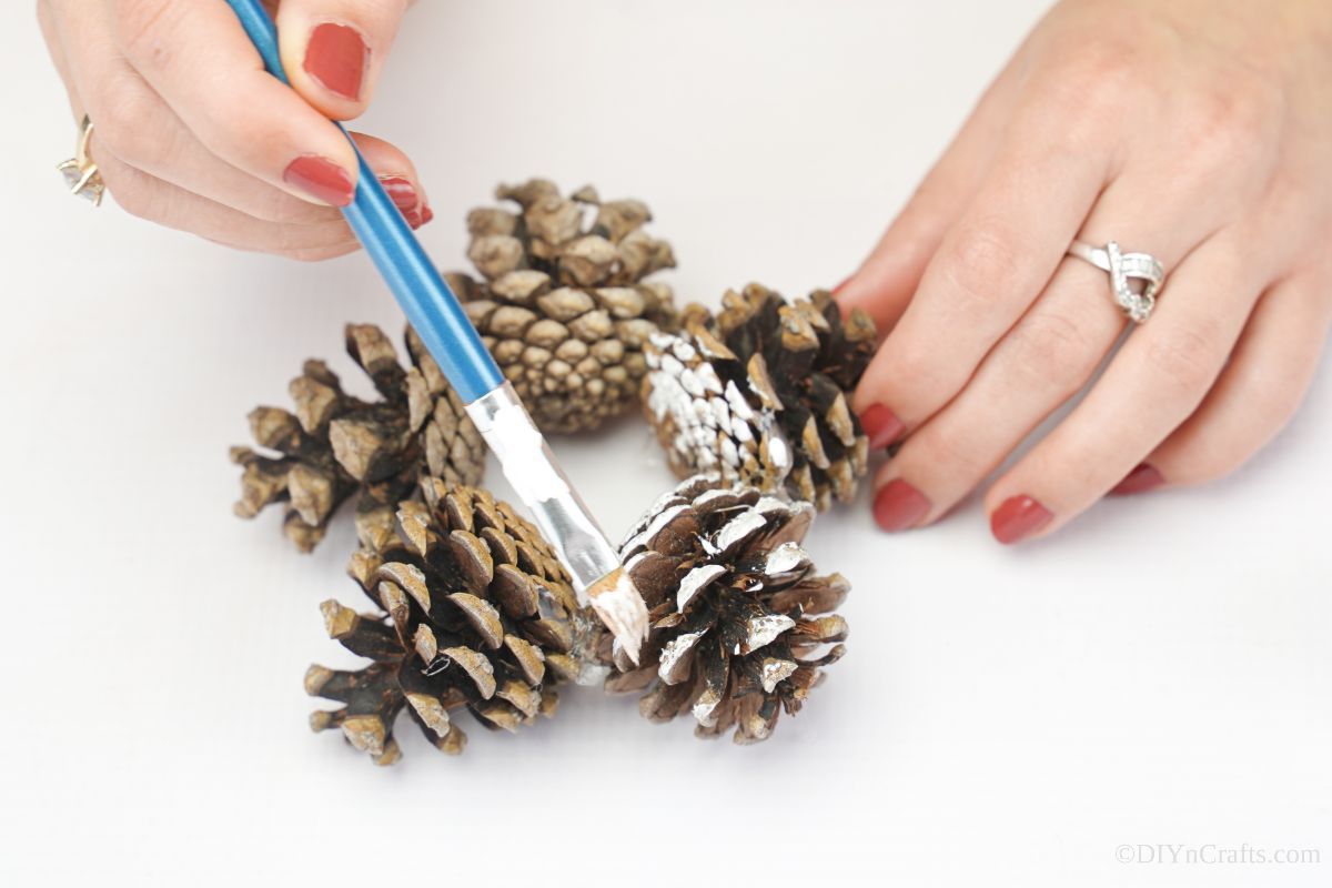 hand painting star shaped pinecone ornament with white paint