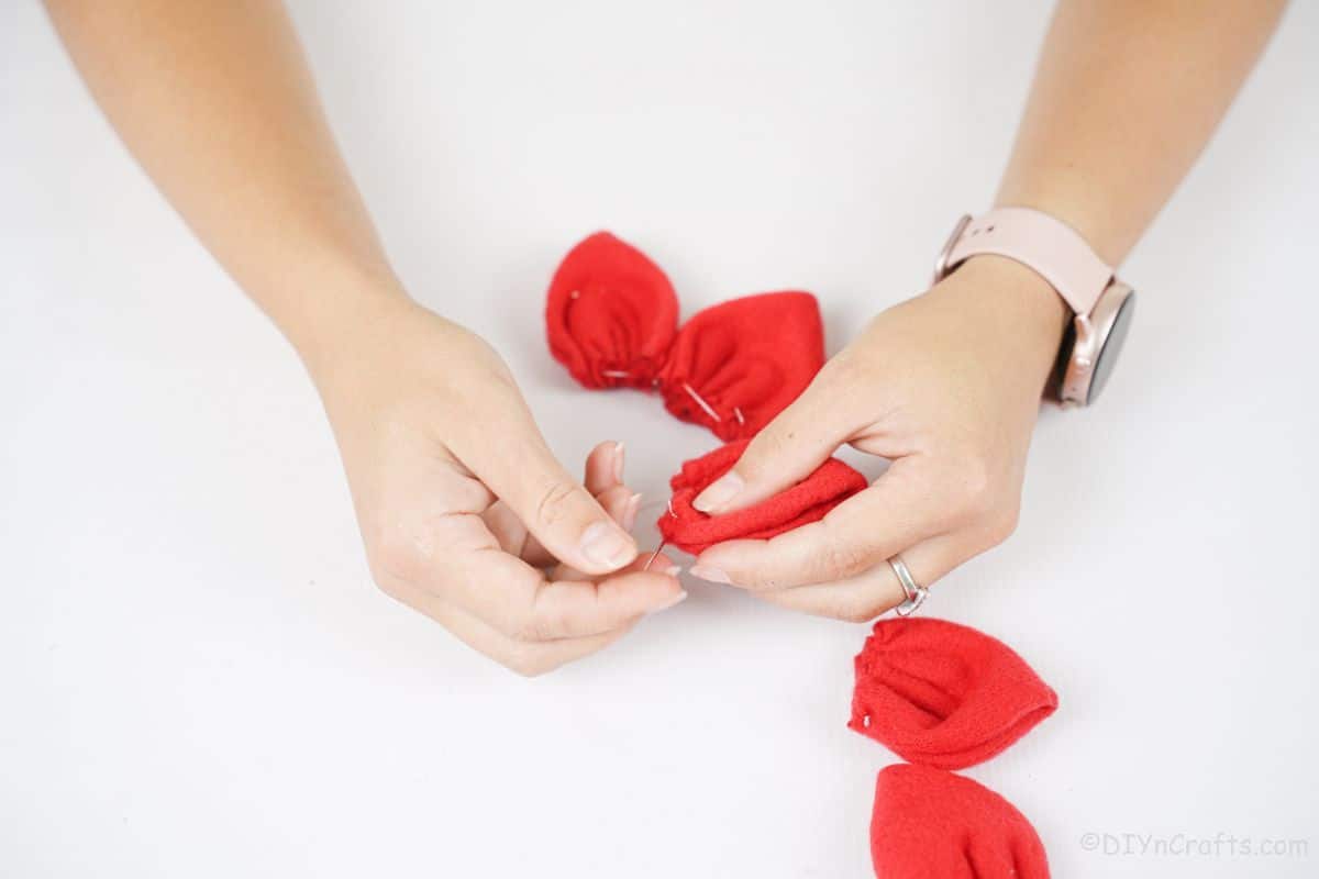 hands holding red fabric with needle an thread