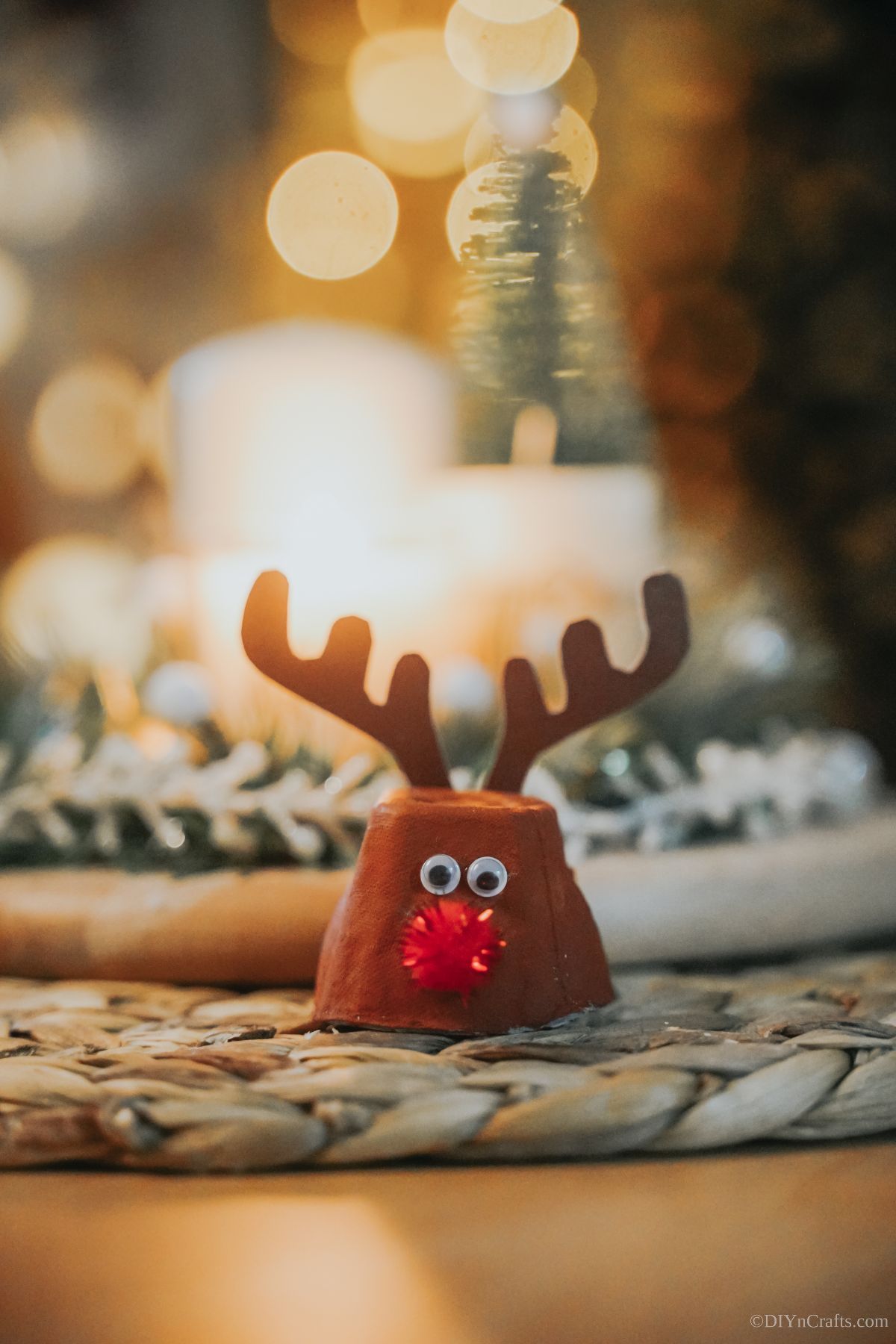 rudolph reindeer made of egg carton cup on table by candle
