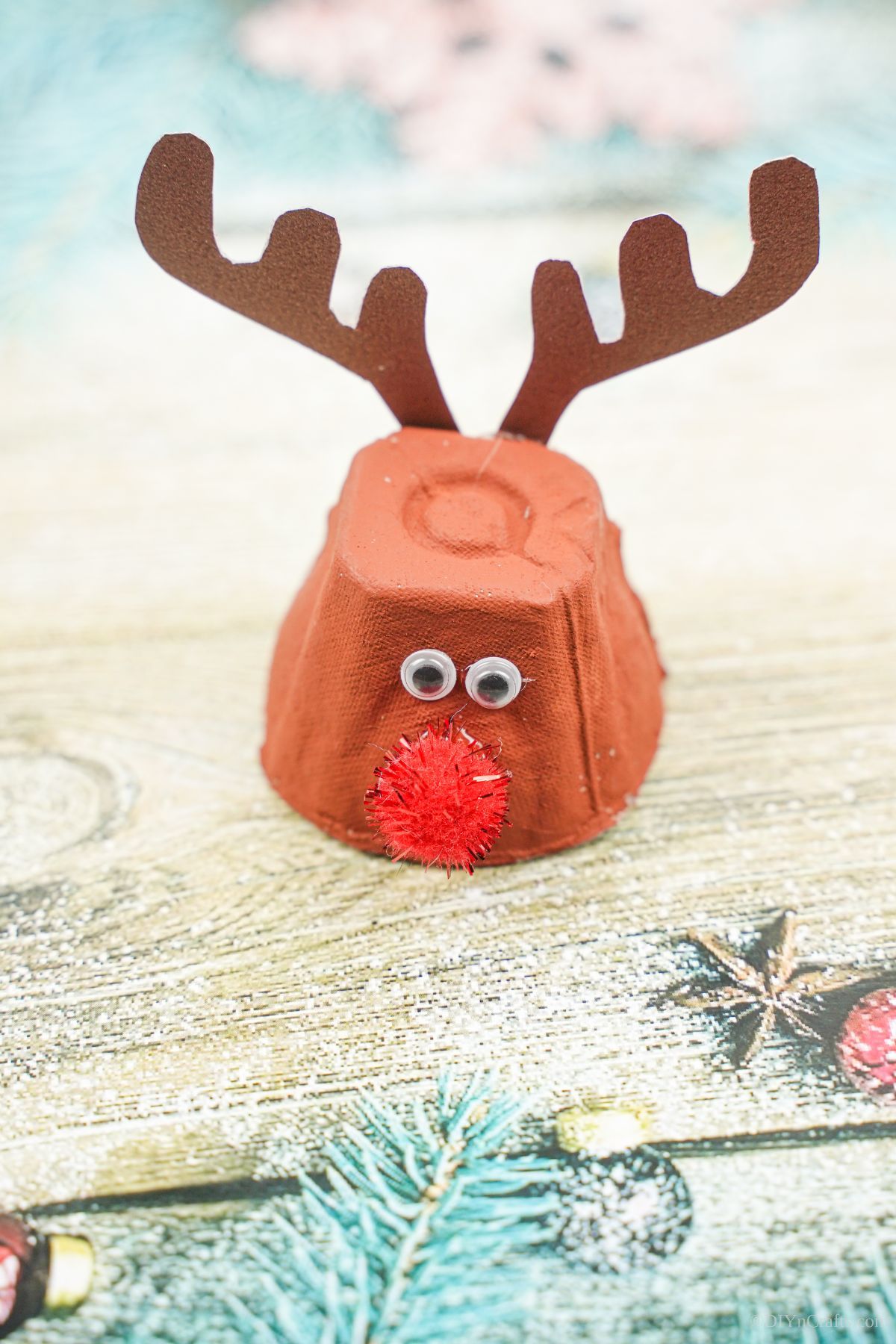 brown egg carton reindeer with red nose on blue wood paper