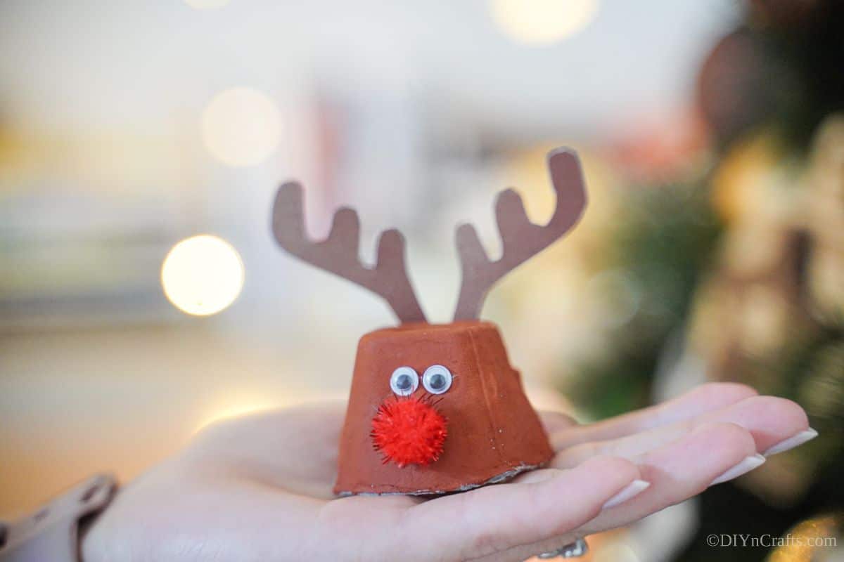 hand holding reindeer made from egg carton