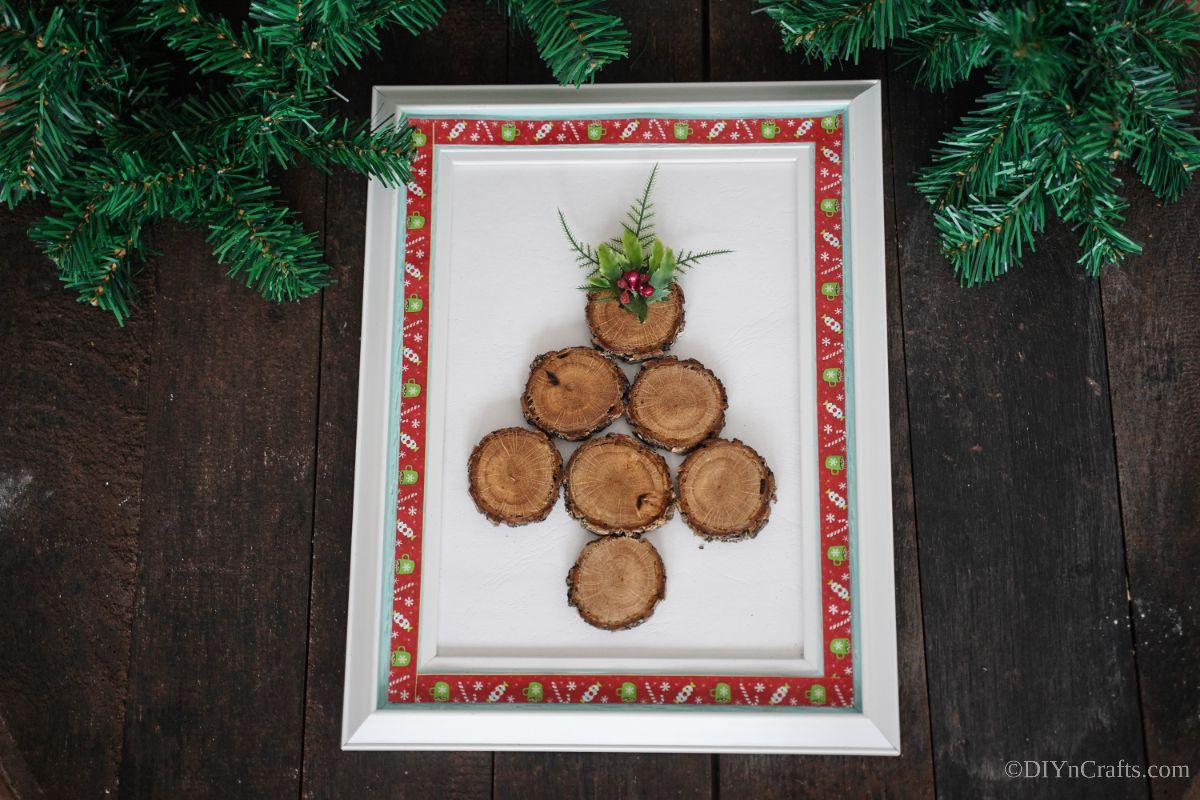 white and red picture frame with wood tree on table by greenery
