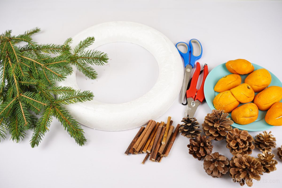 wreath form on table with pinecones cinnamon sticks and orange