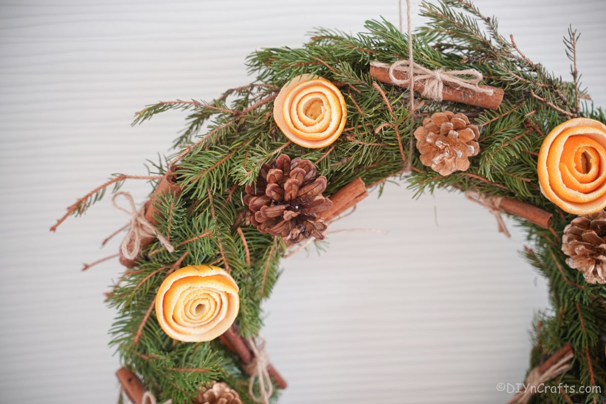 top of green wreath with orange peel roses and pinecones