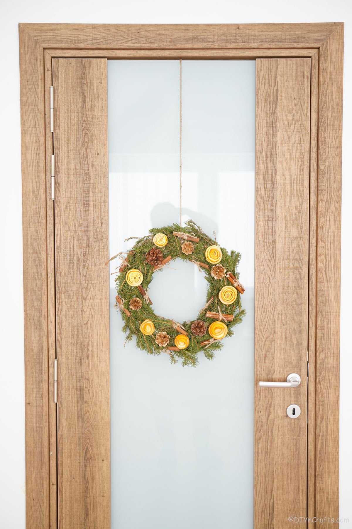 green wreath with orange peel roses on glass door with wood trim