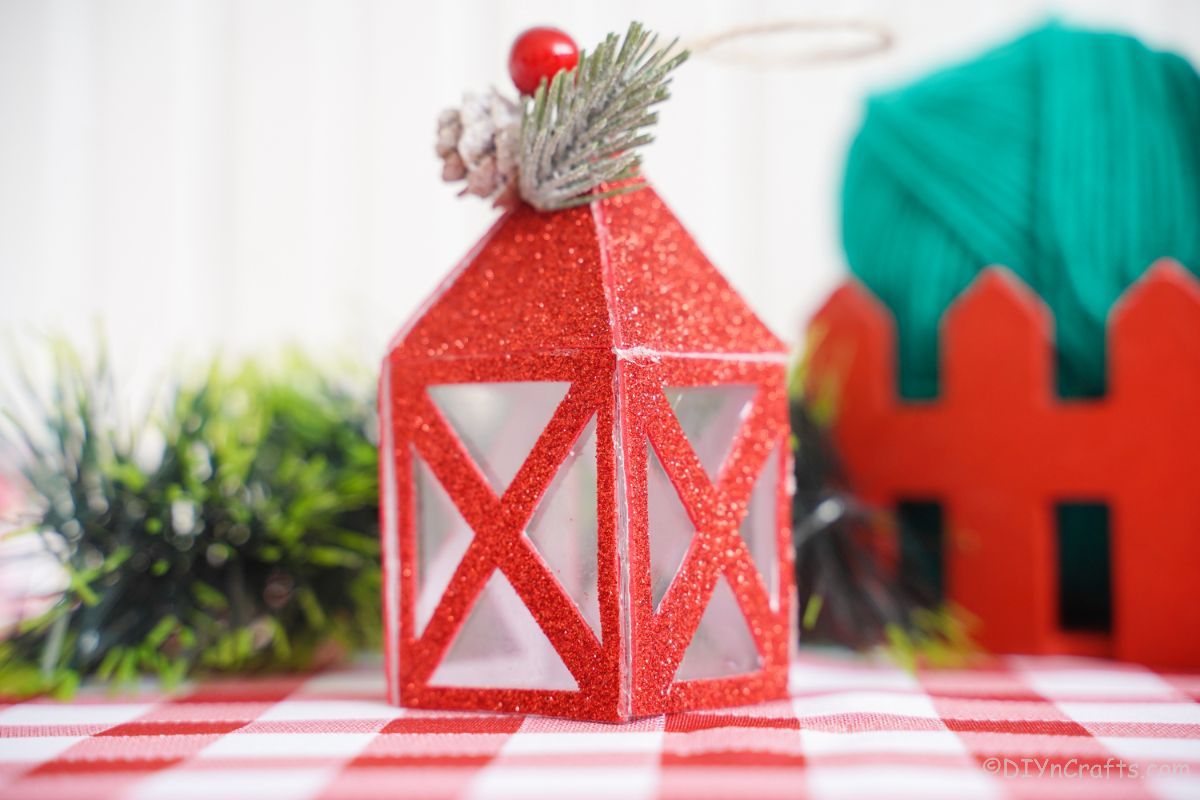 mini paper lantern in front of greenery on red and white checked tablecloth