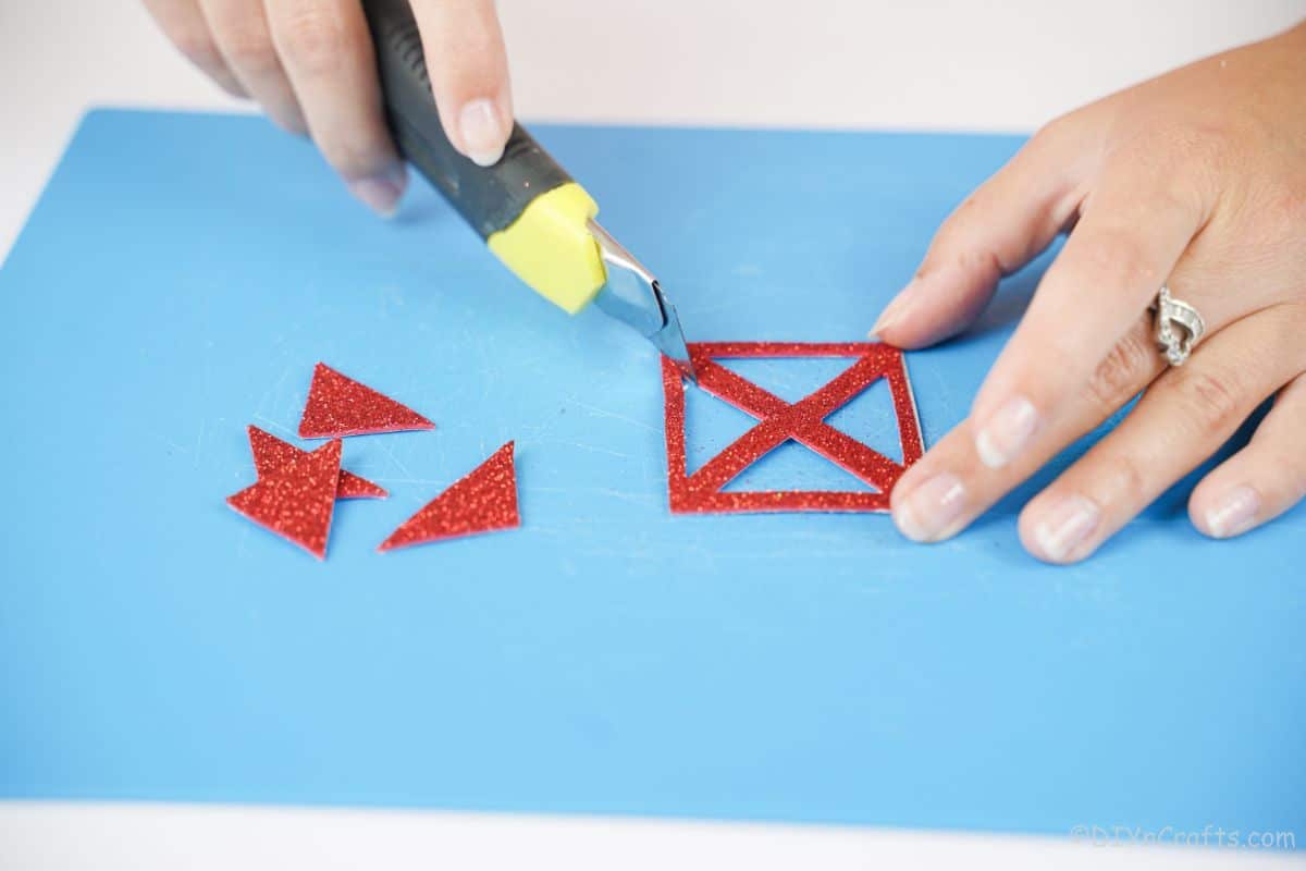 craft knife cutting windows out of red glitter paper