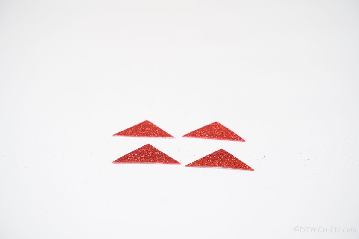 four red glitter triangles on white table