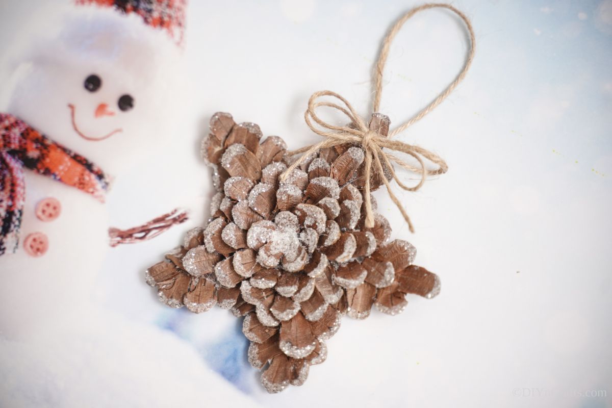 glitter pinecone star on paper with snowman decoration