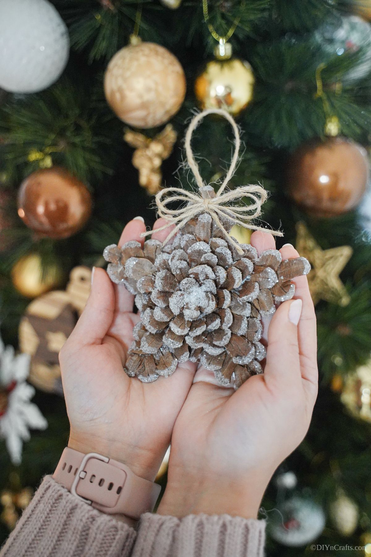 star ornament made of pinecone scales being held in front of tree