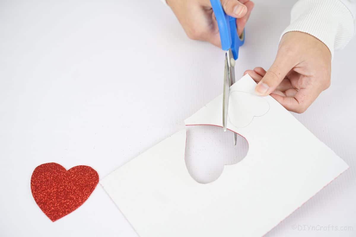 blue scissors cutting heart out of craft paper
