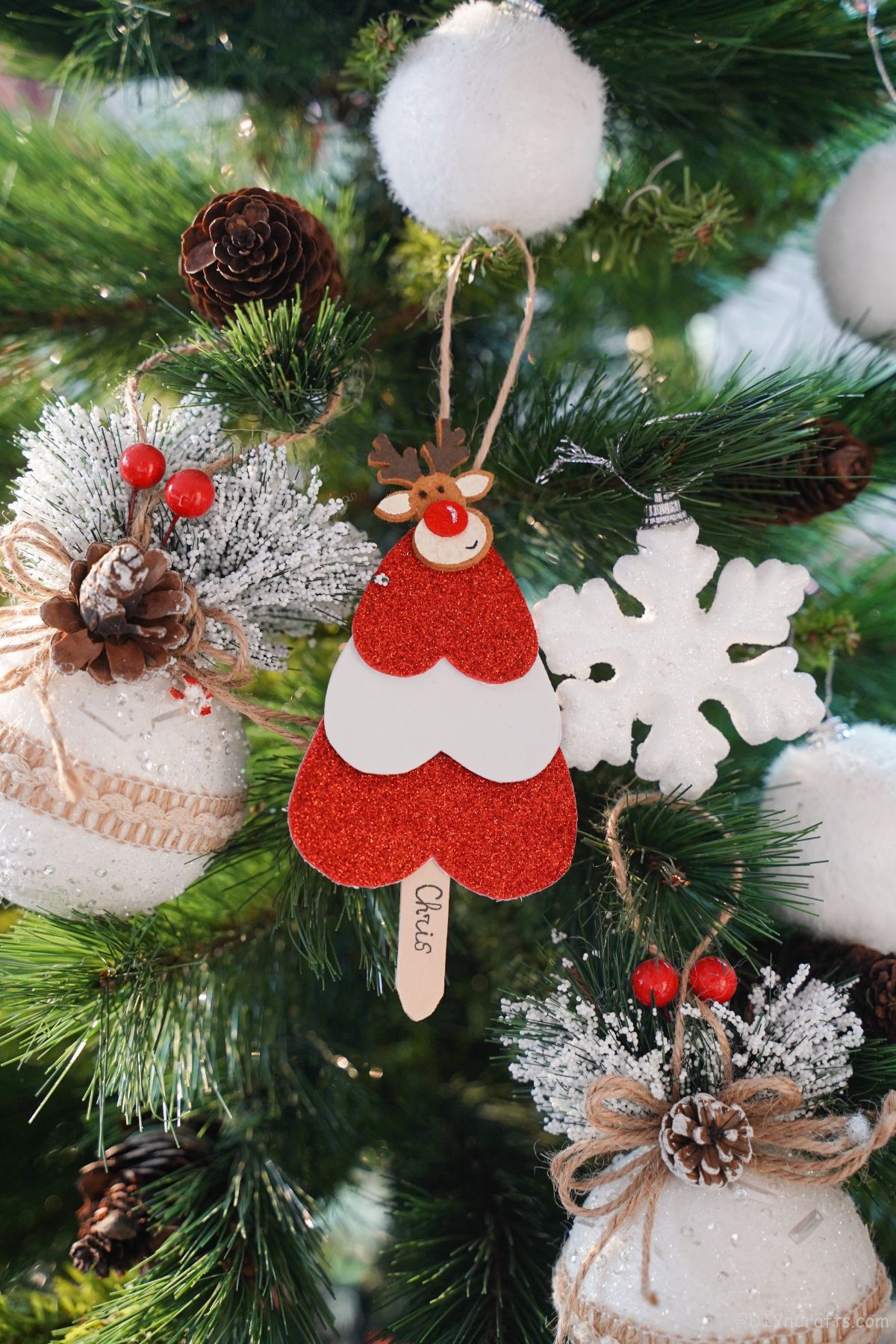 miniaturni rdeči in beli božični okraski v obliki drevesa, ki visi na drevesu z belim ornamentom snežinke