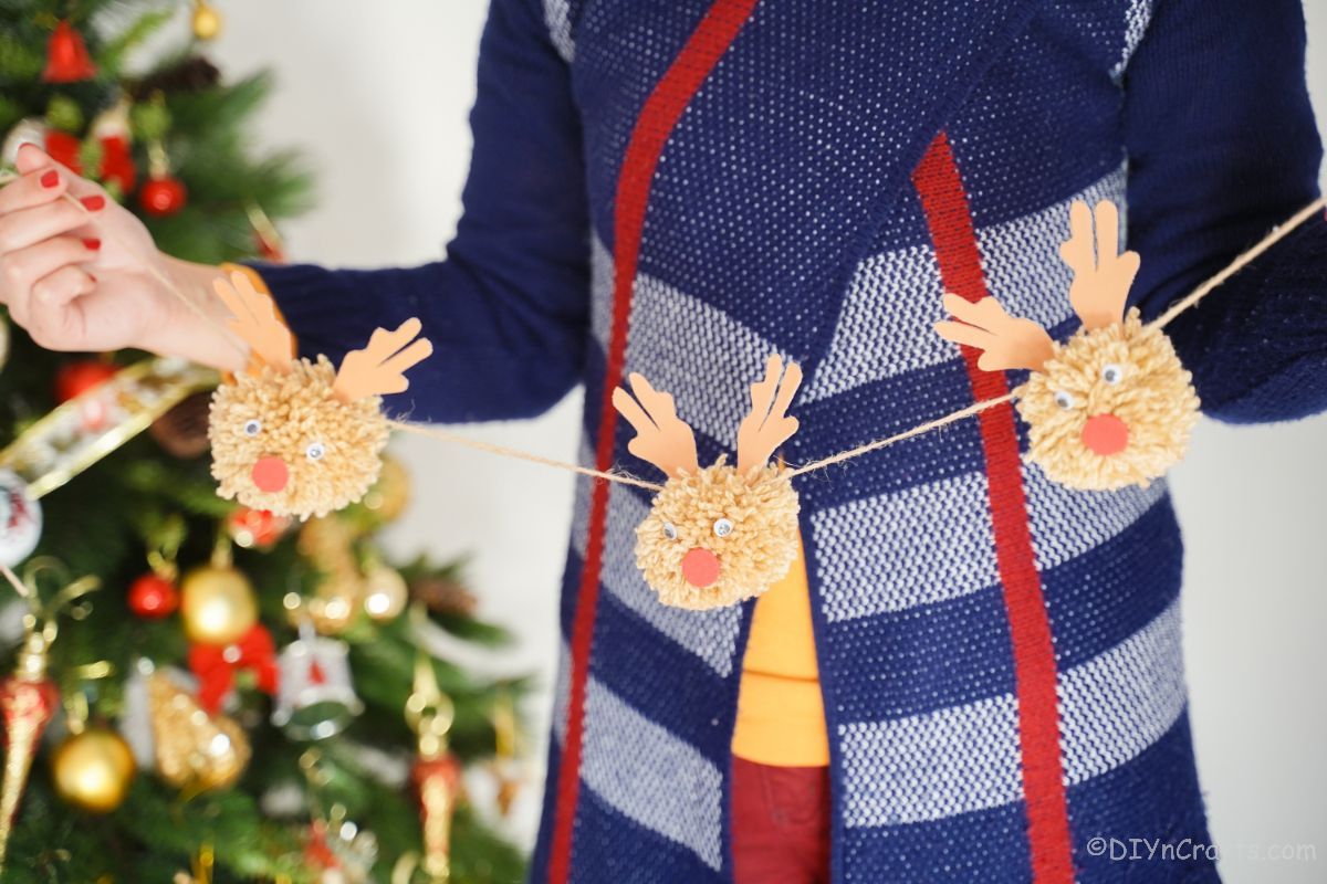 lady in blue sweater holding a reindeer garland