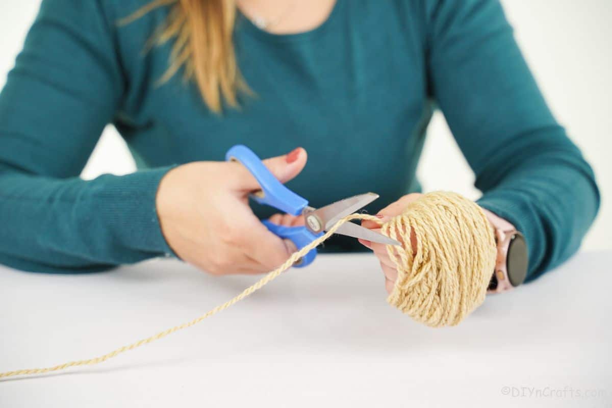 woman cutting yarn with blue scissors