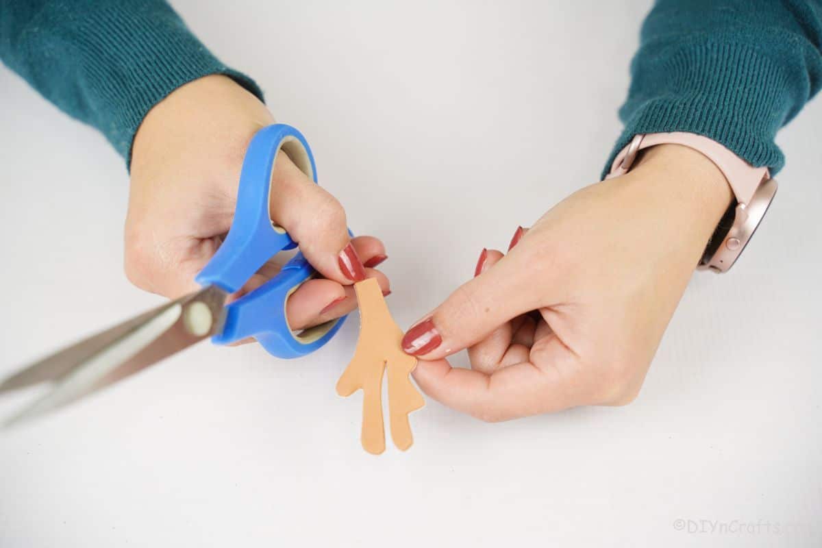 hand holding blue scissors and brown paper antler