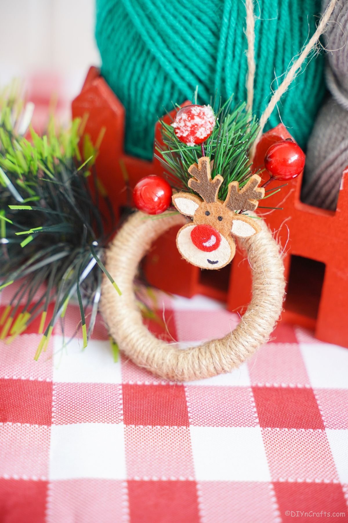 mini wreath ornament leaning against red basket on examined tablecloth