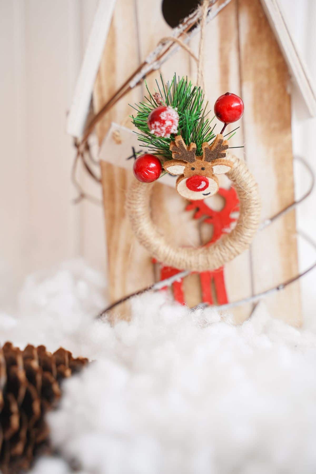 mini rustic wreath on wooden birdhouse sitting on fake snow